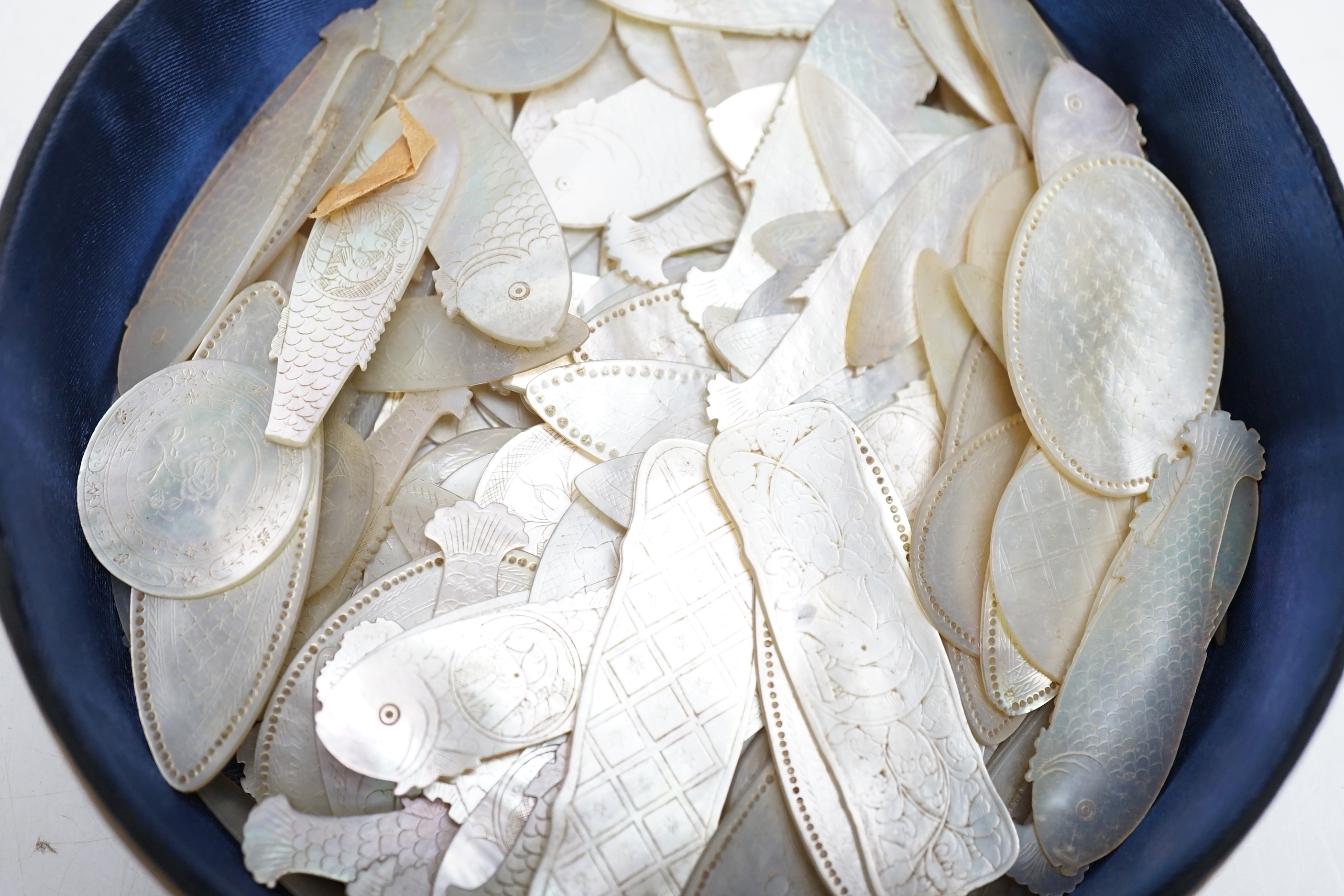 A collection of Chinese mother of pearl fish and other shaped counters